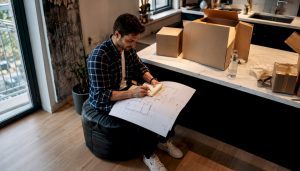 Un homme assis au milieu de son appartement désert, réfléchissant à son prochain déménagement.
