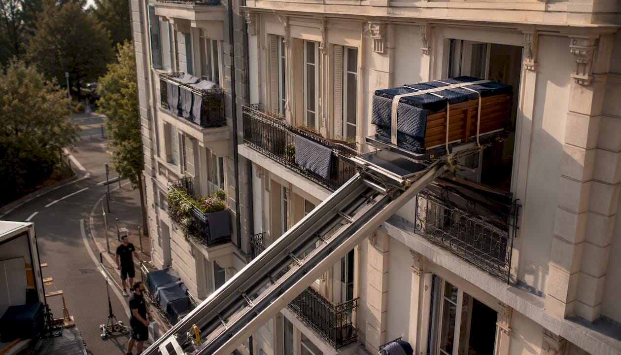 Un monte-meubles en train de hisser des meubles par la fenêtre d’un appartement