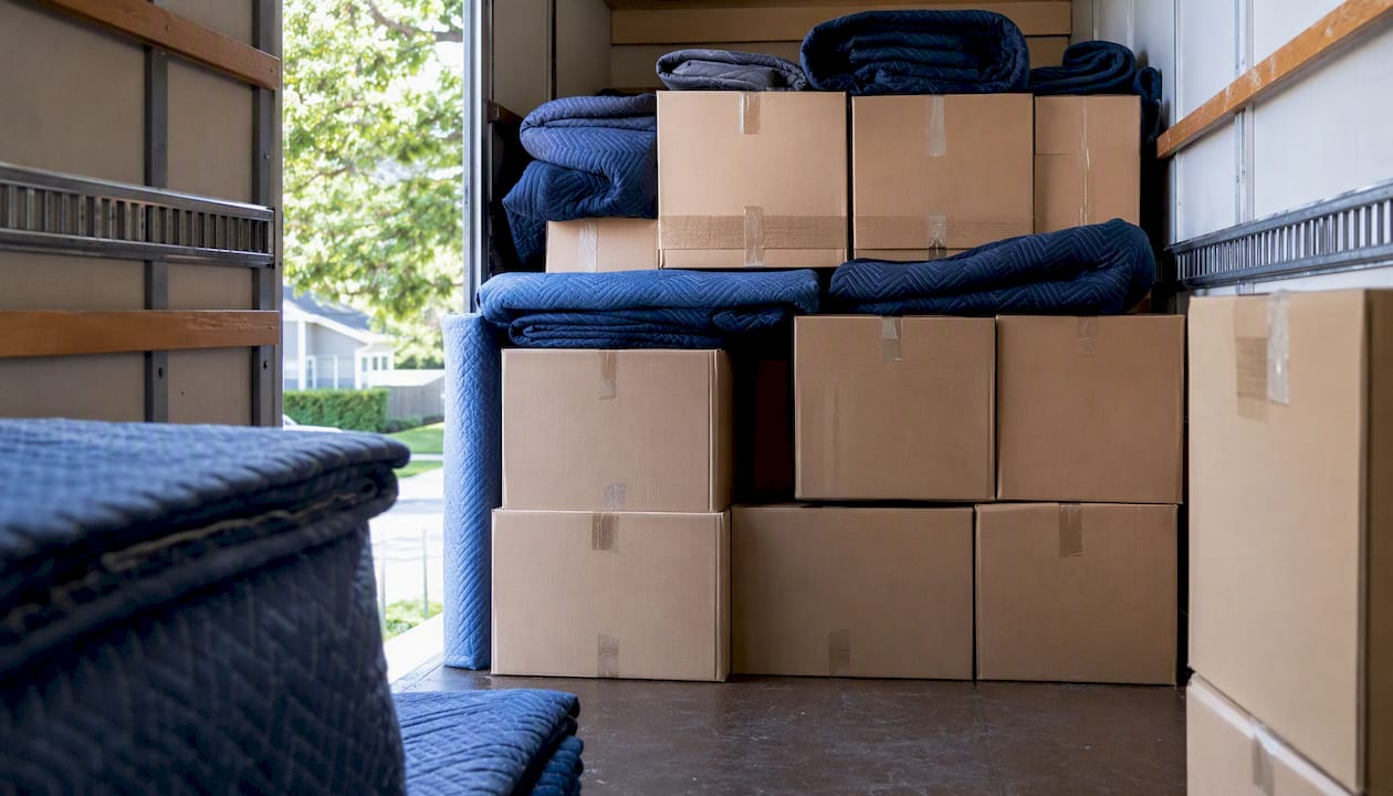 Des cartons de déménagement empilés, avec de la vaisselle fragile posée tout en haut.