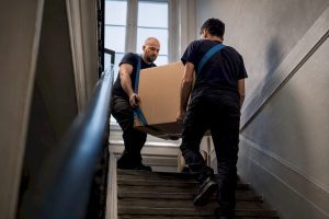 Des déménageurs transportant un carton dans un escalier