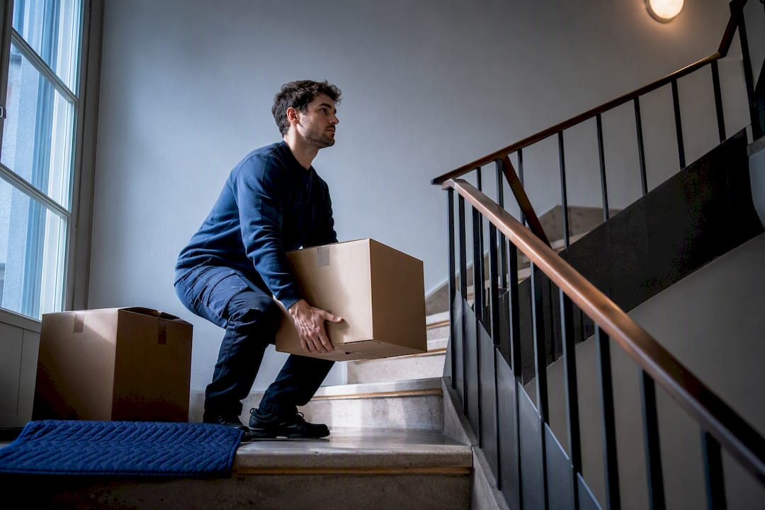 Une personne soulève correctement un carton